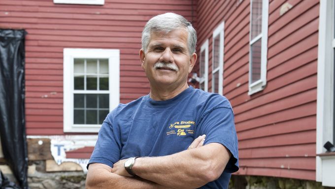 An image of Tom Silva standing in front of a red home.